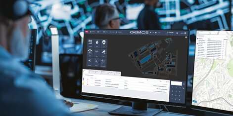 Das Gebäudemanagementsystem GEMOS im Einsatz in einer Sicherheitszentrale. Ein Mitarbeiter sitzt vor mehreren Monitoren.