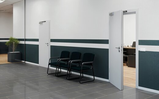 Personen verlassen im Alarmfall ein Bürogebäude durch eine Fluchttüre. 