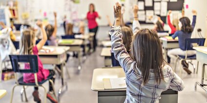 Schüler heben Hände im Unterricht