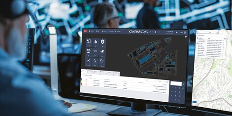 Mitarbeiter bedient das Gebäudemanagementsystem GEMOS an mehreren Monitoren in der Sicherheitszentrale