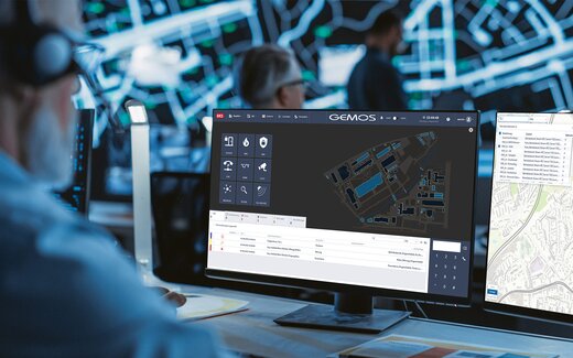 Person mit Headset steuert im Kontrollraum die Überwachungssoftware GEMOS an mehreren Monitoren
