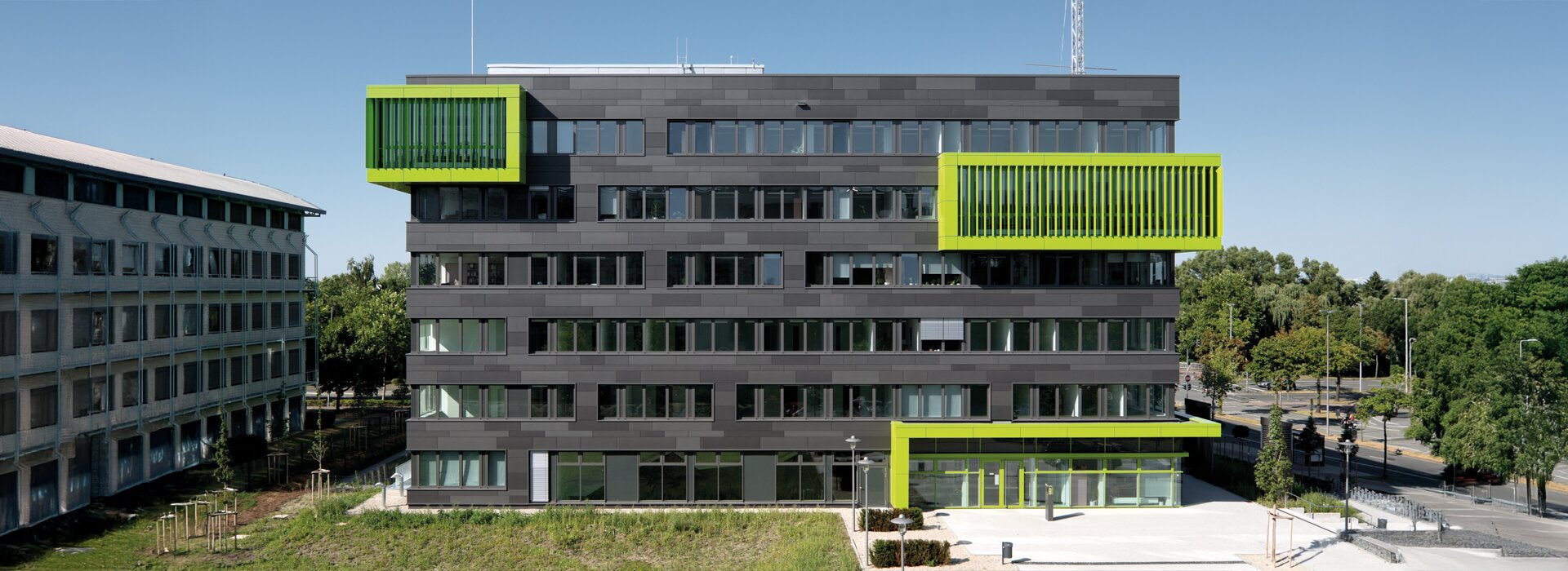 Modernes graues Universitätsgebäude mit grünen Akzenten