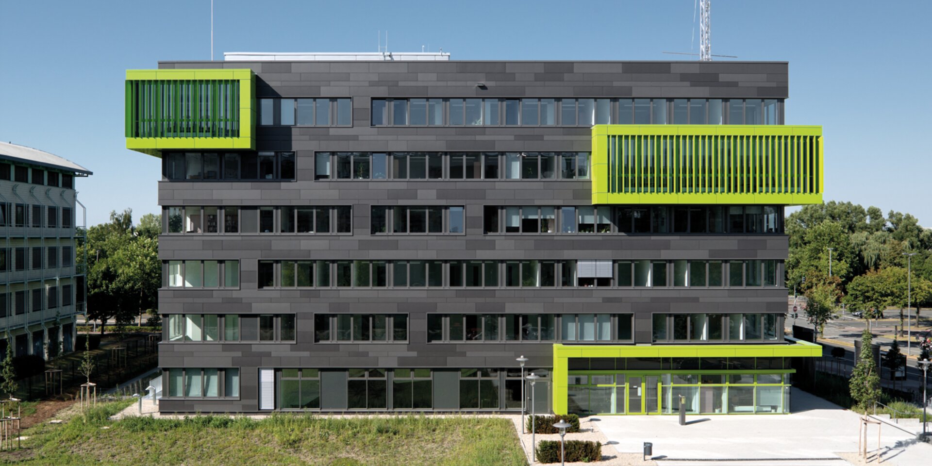 Modernes graues Universitätsgebäude mit grünen Akzenten